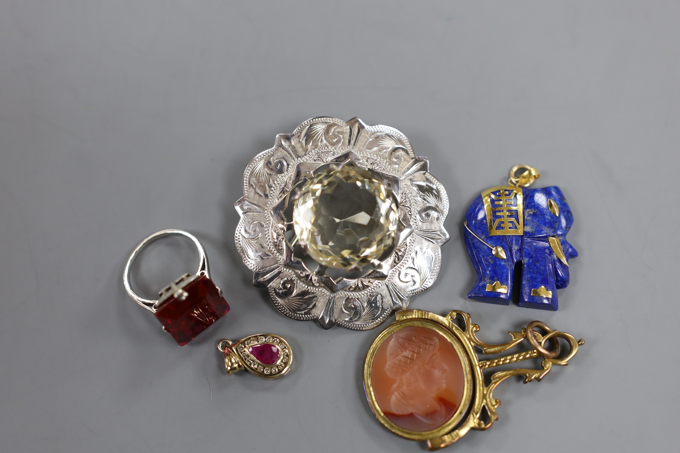 A modern yellow metal, ruby and diamond cluster set pear shaped pendant, overall 20mm, a Scottish silver mounted citrine brooch, a 9k mounted lapis lazuli elephant pendant, a 9ct dress ring, a gilt metal mounted and inta